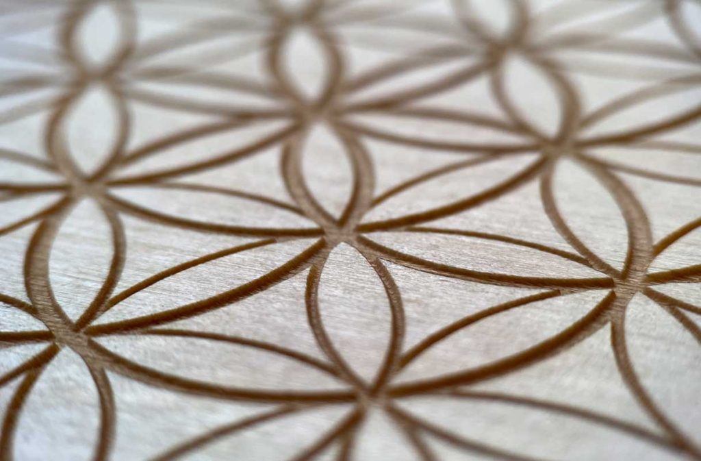 Gravur der Blume des Lebens auf der T-woodibox, symbolisiert Harmonie und Energie